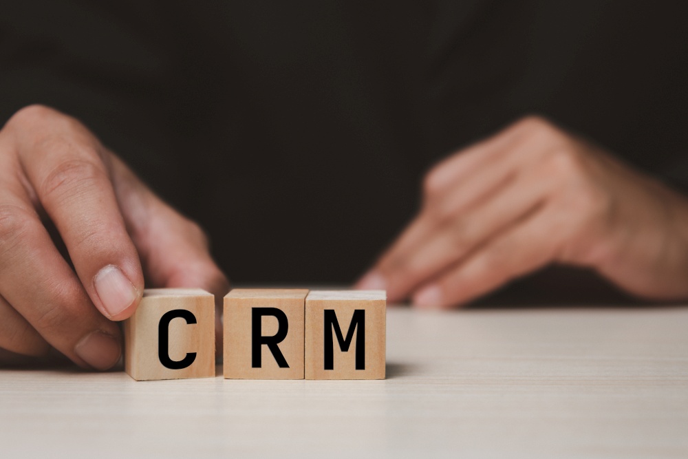 Wooden cubes with CRM Customer relationship management automation system software symbol on desk and copy space.Business concepts.