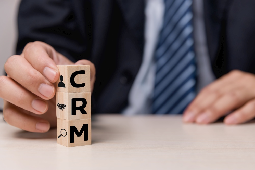 Wooden cubes with CRM Customer relationship management automation system software symbol on desk and copy space.Business concepts.