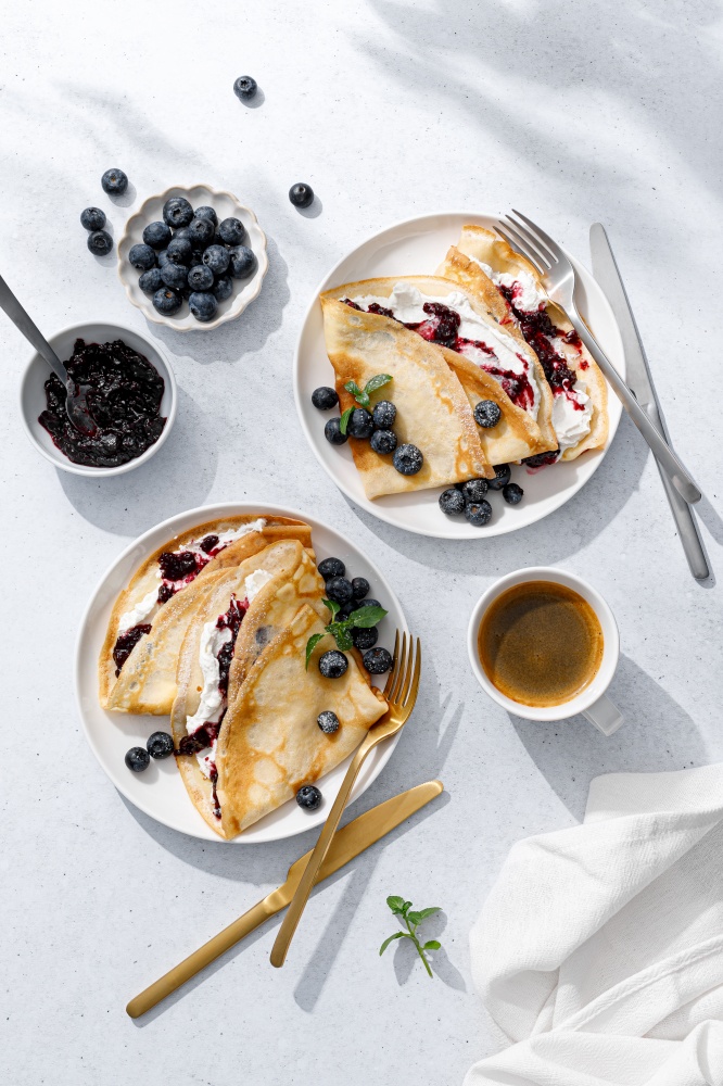 Crepes with blueberry jam, ricotta cheese and fresh berries. Pancakes for breakfast. Top view
