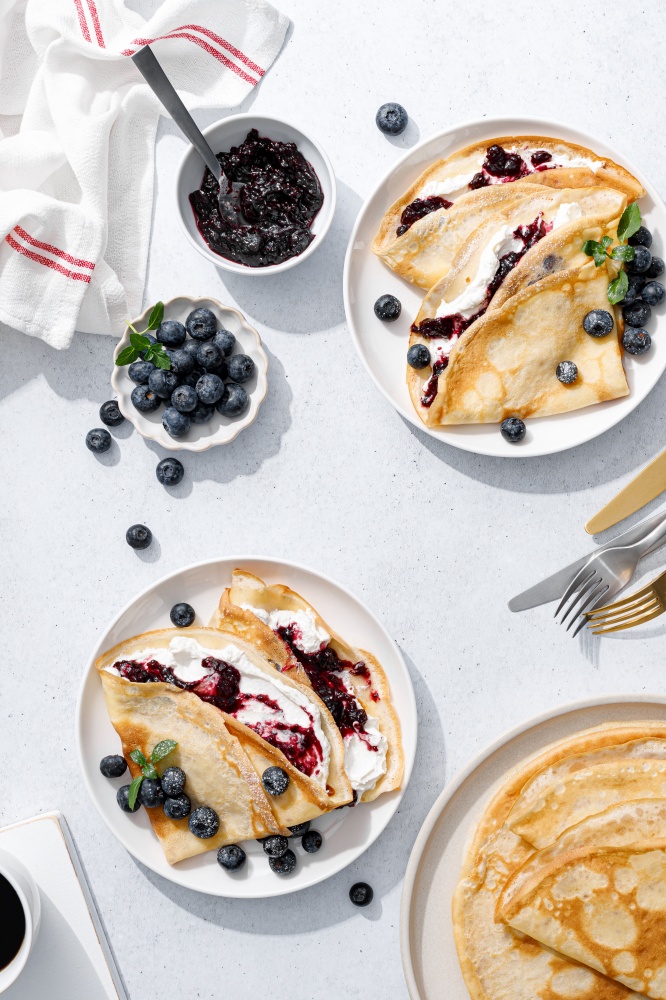 Crepes with blueberry jam, ricotta cheese and fresh berries. Pancakes for breakfast. Top view