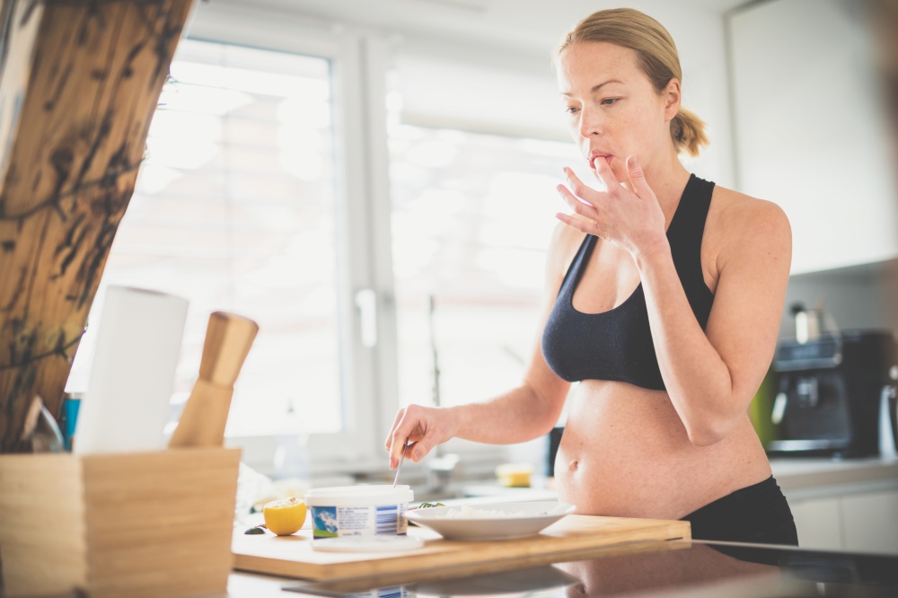 Beautiful sporty fit young pregnant woman preparing healthy meal in home kitchen. Healty lifestyle concept. Beautiful sporty fit young pregnant woman preparing healthy meal in home kitchen. Healty lifestyle concept.