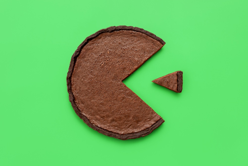 Above view with a chocolate tart minimalist on a green table. Pie chart concept with a small slice of cake next to a bigger piece.