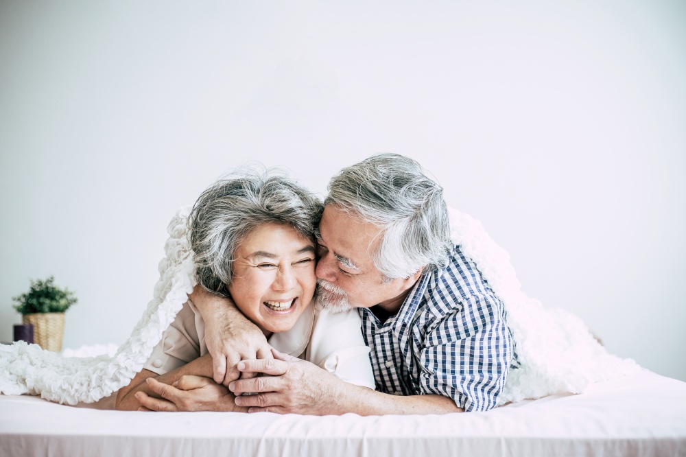Happy senior couple laughing in bedroom