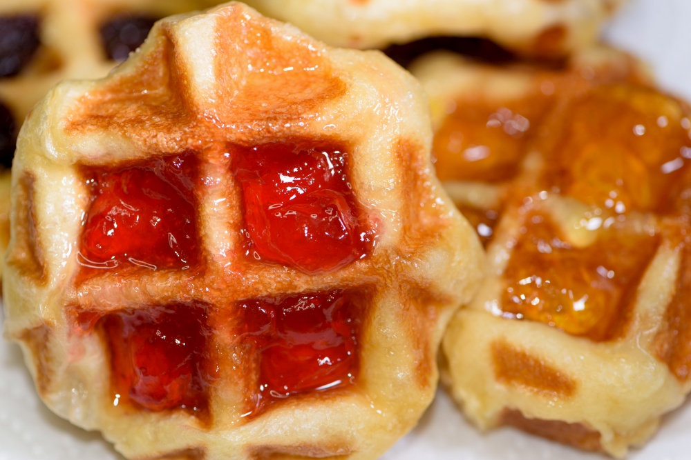 Close up of fresh waffles topped with delicious sweet strawberry jam and pineapple jam on top. Make homemade food or snacks at home. Close up fresh waffles with above strawberry jam