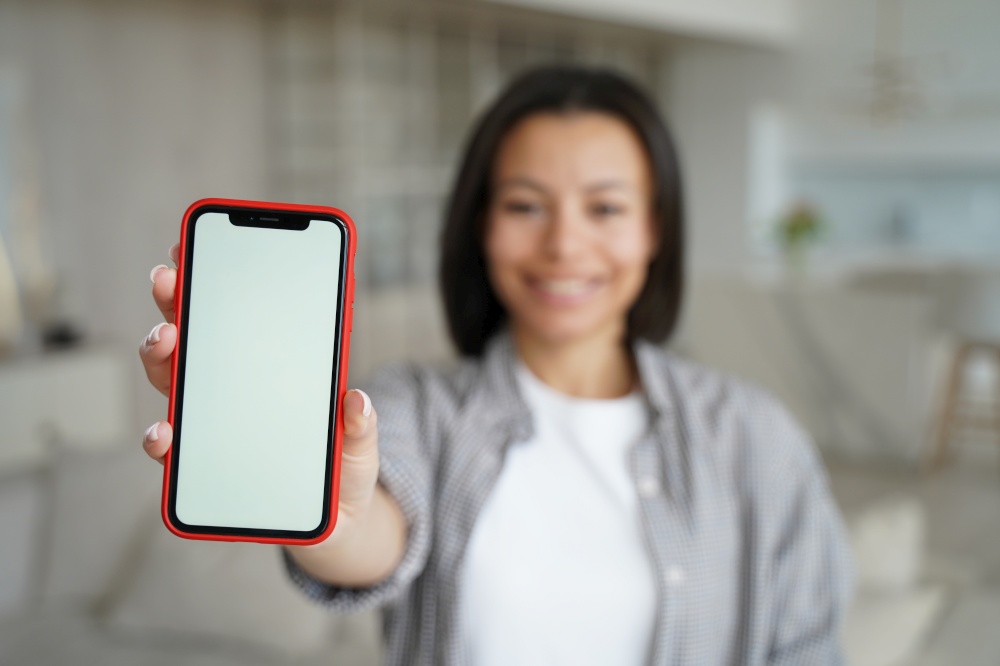 Woman showing smartphone with blank mock up screen at home. Close-up female hand holding phone with empty template screen. New apps advertisement, big discounts in online store, best offer concept.. Closeup female hand showing phone with blank mock up screen. Apps advertisement, online store offer