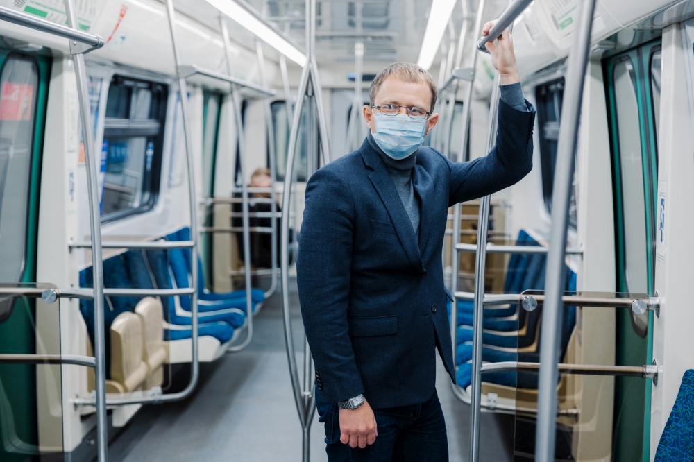 Coronavirus crisis in 2020. Man commutes to work in empty underground, uses public transport, uses protective face mask against virus, wears protective surgical mask during quarantine period