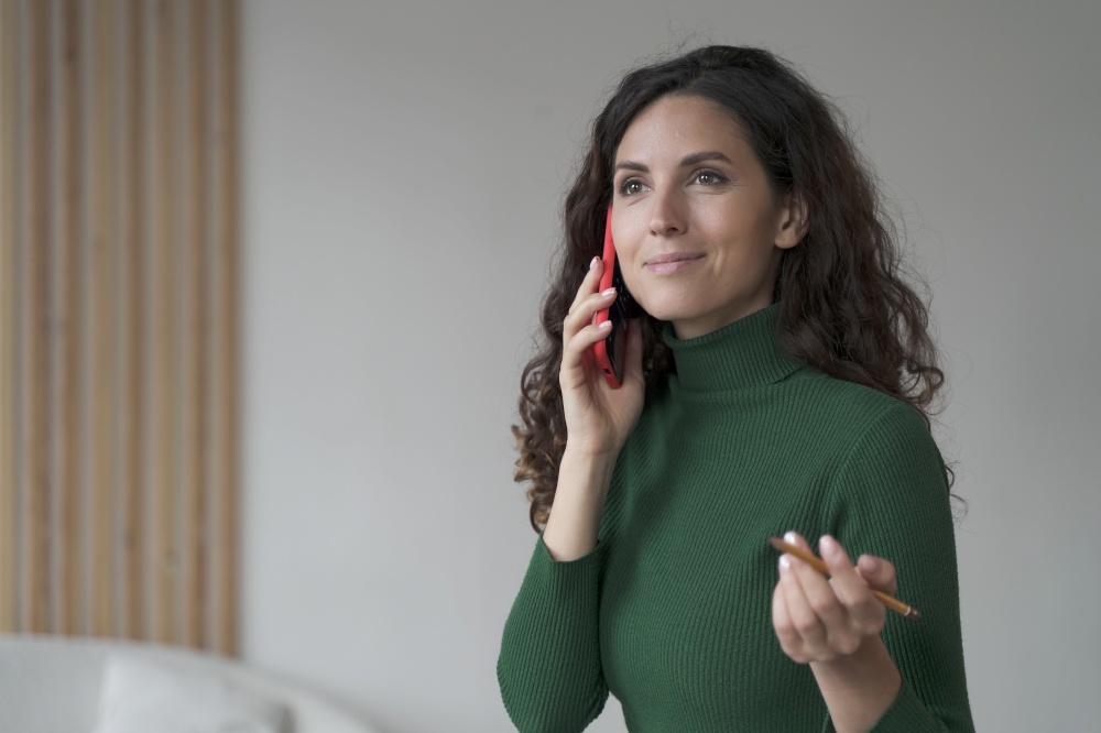 Attractive Spanish young businesswoman enjoying telephone conversation with partner, woman using modern smartphone at work, smiling female office worker consulting client via mobile. Attractive Spanish young businesswoman enjoying telephone conversation, using smartphone at work
