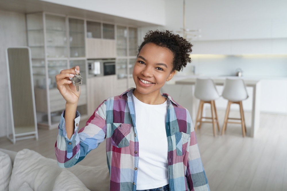 Young biracial girl homeowner tenant showing key to new house, rented or purchased apartment. African american female owner holding bunch of keys standing in modern flat. Relocation, real estate rent.. Happy young biracial girl homeowner tenant shows key to new house. Relocation, real estate rent