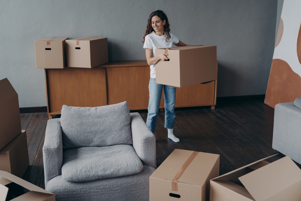 Hispanic girl is holding box and leaving apartment. Happy young woman relocates alone. Single lady moves. Real estate purchase, mortgage, delivery service ordering concept.. Hispanic girl is holding box and leaving apartment. Happy young woman relocates alone.