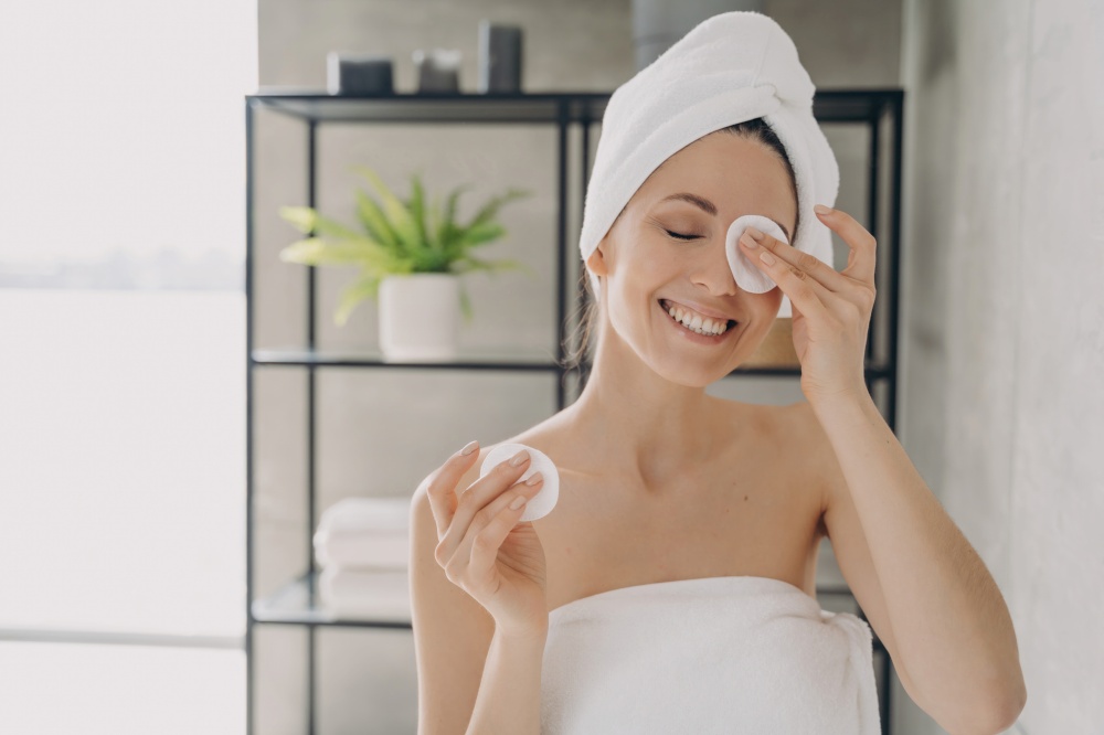 Girl cleanses skin, attractive woman with towel after bathing. Happy woman showers at home. Delicate skin care, purifying.