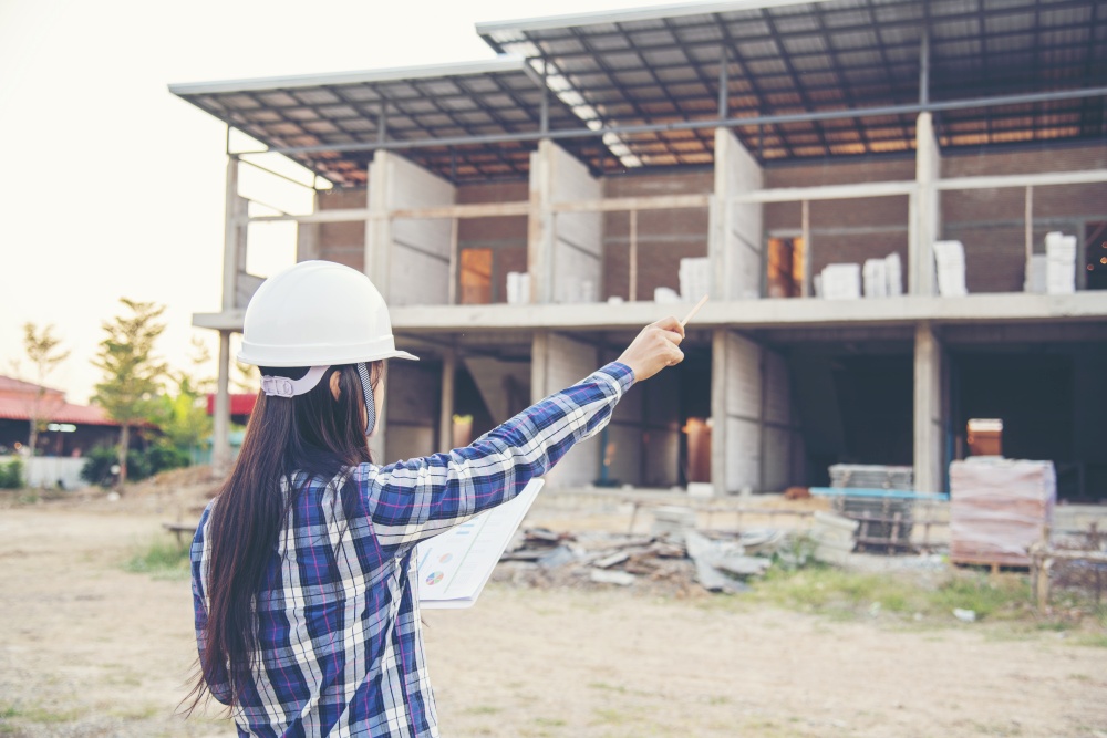 Woman construction engineer hold blueprint wear plaid shirt safety white hard hat at construction site industry labor worker. Architecture Female engineer civil worker look at blueprint real estate