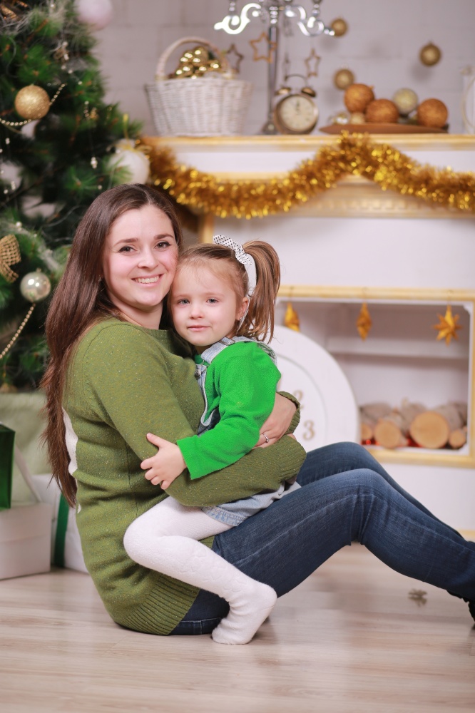 Merry Christmas and Happy Holidays. Pretty young mom with her cute little daughter near Christmas tree with gift boxes indoors.. Merry Christmas and Happy Holidays. Pretty young mom with her cute little daughter near Christmas tree with gift boxes indoors