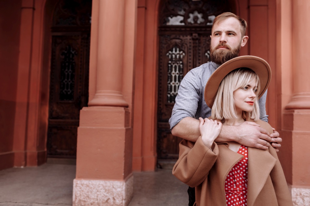 Valentines day. Beautiful stylish happy hipster loving couple is hugging outdoors. Smiling blond woman in hat and bearded man having romantic date at old European city. Concept of love and emotions.. Valentines day. Beautiful stylish happy hipster loving couple is hugging outdoors. Smiling blond woman in hat and bearded man having romantic date at old European city. Concept of love and emotions