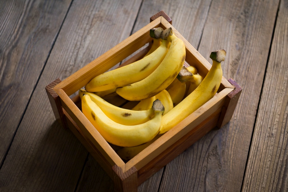 bunch of bananas - banana on wooden box background, ripe banana fruit on floor - top view