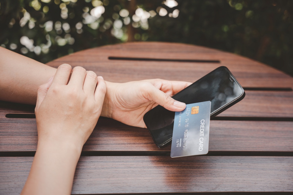 Close up hand of woman using credit card and smartphone during slide screen for finding product purchase buying payments online shopping, making secure internet payment browsing banking service