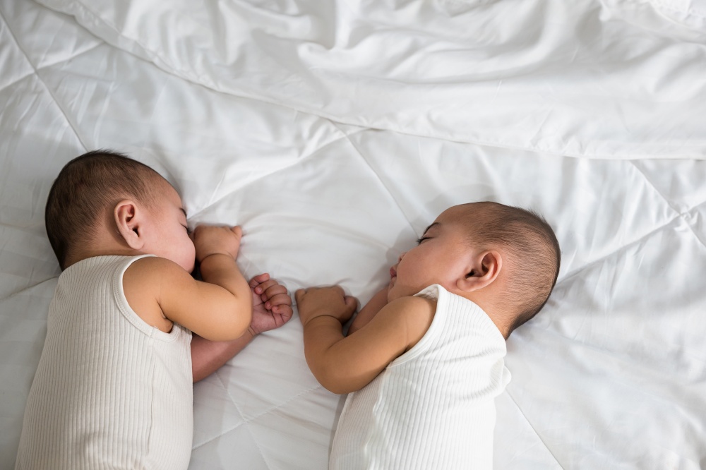 Asian two adorable twin babies boy, Happy childhood, Sleeping newborn identical boy twins on the bed on bedroom, family people infant