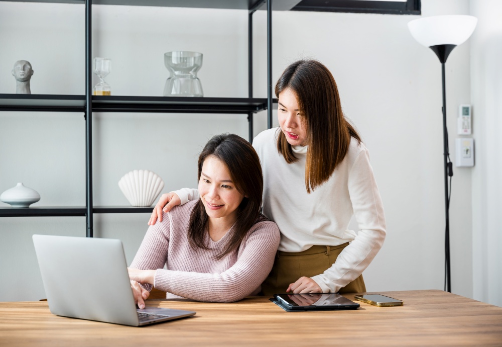 Asian middle age woman and teen they shoping online on computer, mother and teenage daughter looking at laptop computer at home office, happy family work together