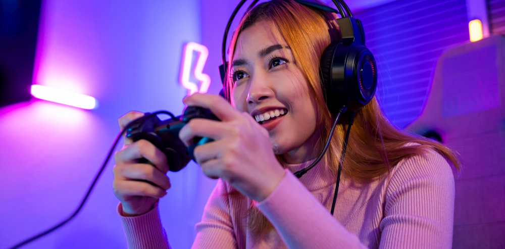 You win. Gamer using joystick controller plays online video game with computer neon lights she winning, woman wear gaming headphones playing live stream esports games console at home celebrating win
