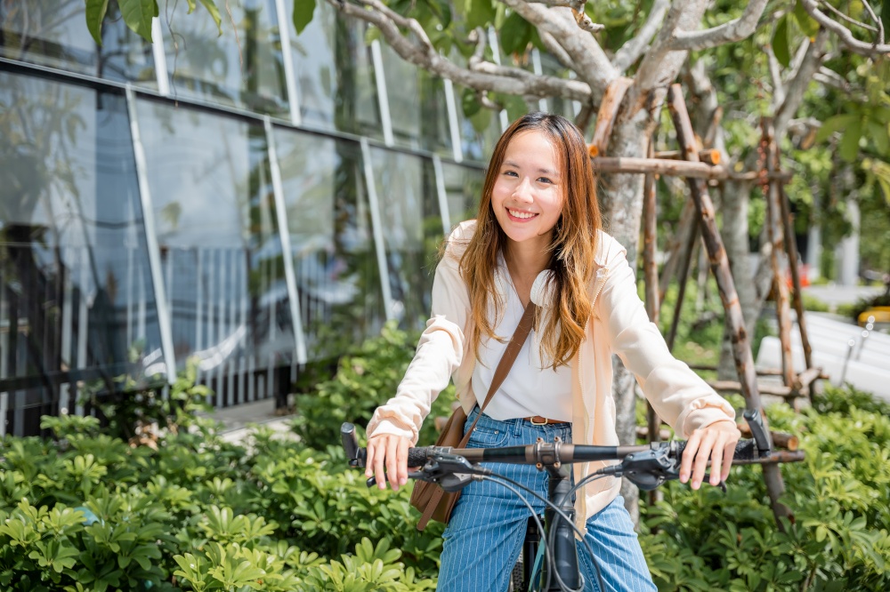 Portrait of smiling female lifestyle using bike in summer travel means of transportation, Happy Asian beautiful young woman riding bicycle on street outdoor near building city, ECO friendly concept