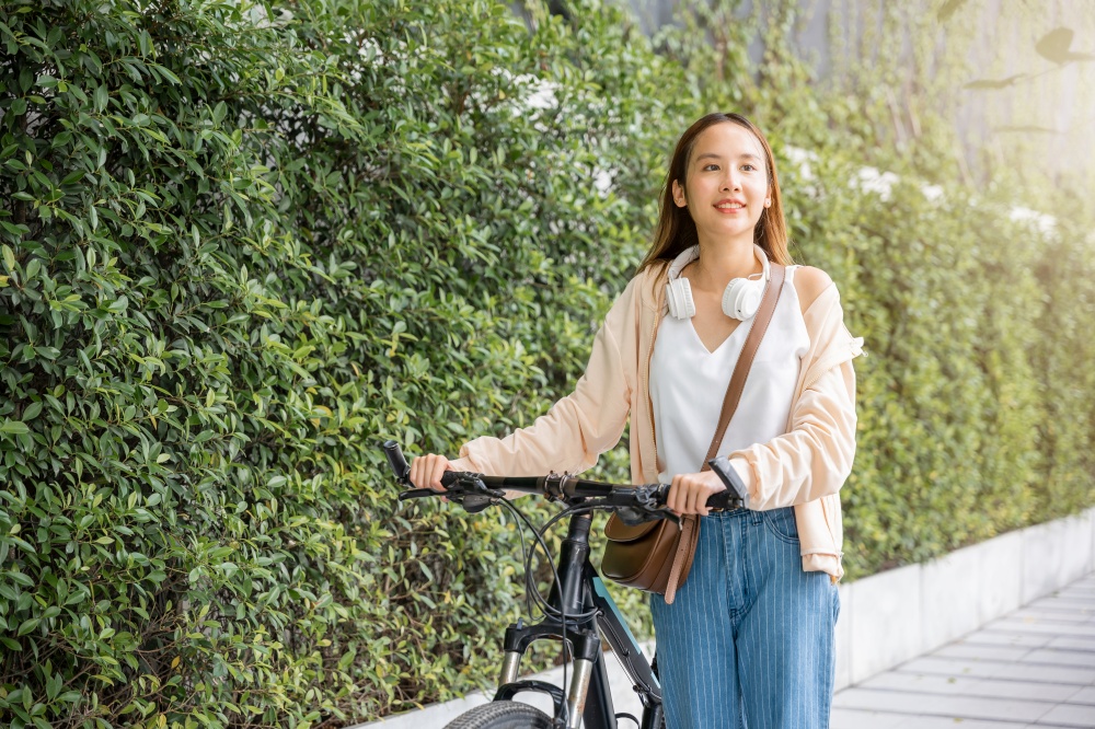 Happy female smiling walk down the street with her bike on city road, ECO environment, healthy holiday travel, Asian young woman walking alongside with bicycle on summer in park countryside outdoor