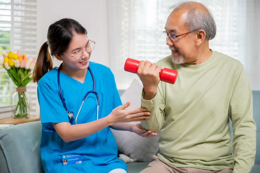 Asian nurse physiotherapist helping senior man in lifting dumbell at retirement home, Young nurse take care support training elderly sitting on sofa using dumbbell workout exercise, Healthcare medical