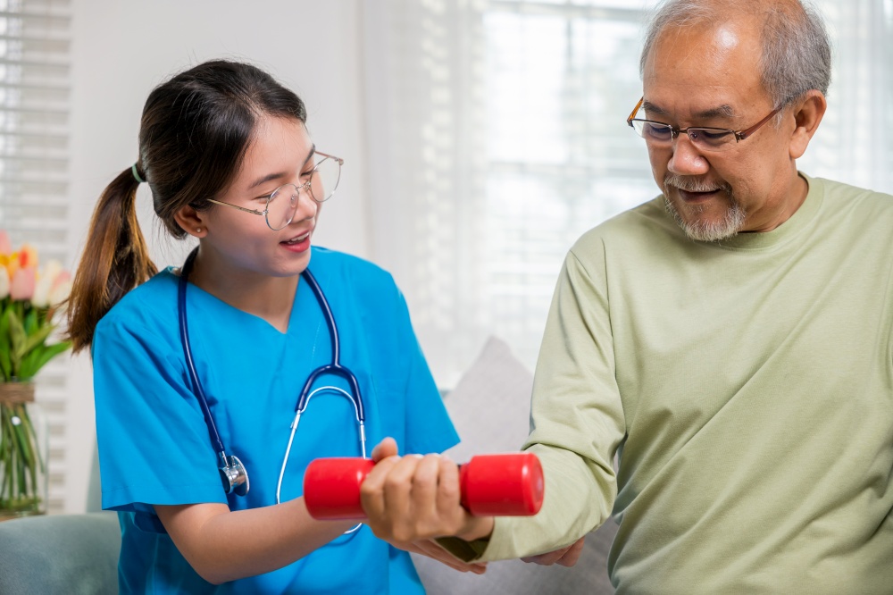 Young nurse physiotherapist support senior old man to lifting dumbell at home, nursing help elderly retirement training using dumbbell to workout exercise physical recovery, Health care and medicine