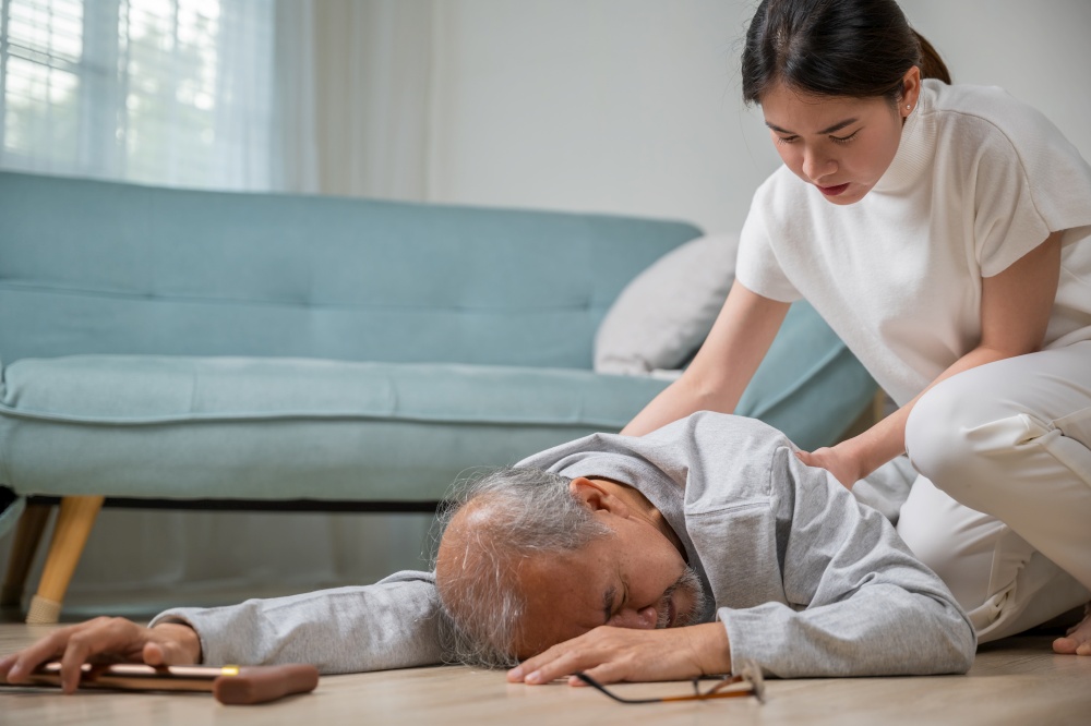Asia young woman halping her father after falling down on floor, elderly old man with walking stick fall on ground and daughter camp to help at home in living room, family health care