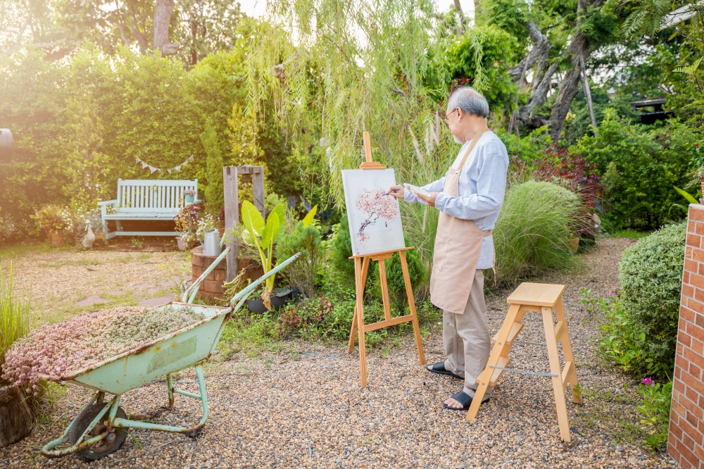 Lifestyle elderly people smile paint at his easel outside home, Asian senior old man painting picture using brush and oil color on canvas, Happy retirement artist and activity concept