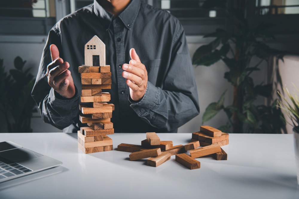 Hands stop domino effect before destroy home before fail, Hand of engineer man protection blocks wood tower, business risk and strategy dangerous project, Insurance concept