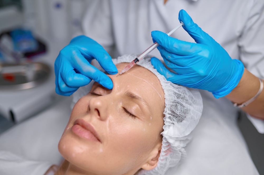 Anti-aging treatment and filler injection into eyebrow. Side view cosmetologist putting puncture of patient skin. Anti-aging treatment and filler injection between eyebrow concept