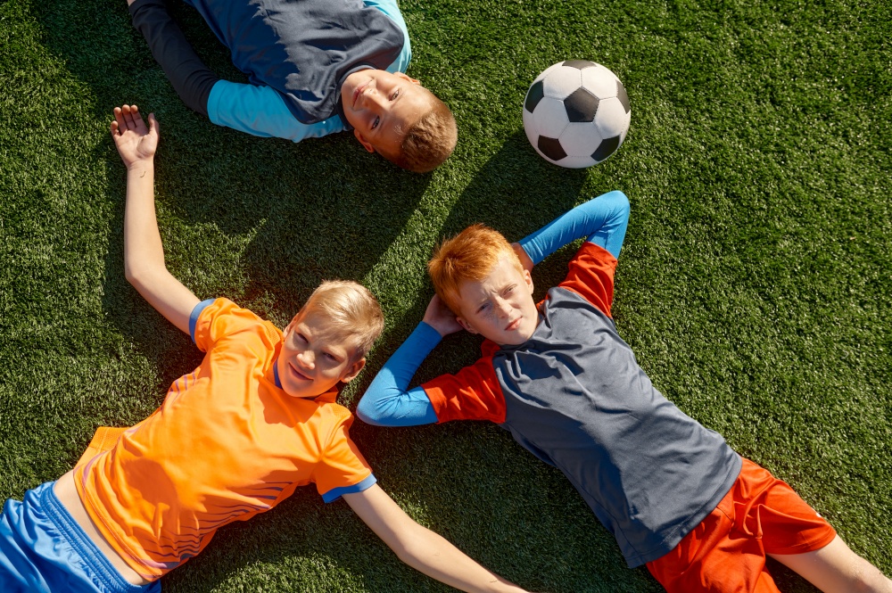 Overhead view on little football player lying while resting after training at soccer sport school. Overhead view on little football player lying while resting after training