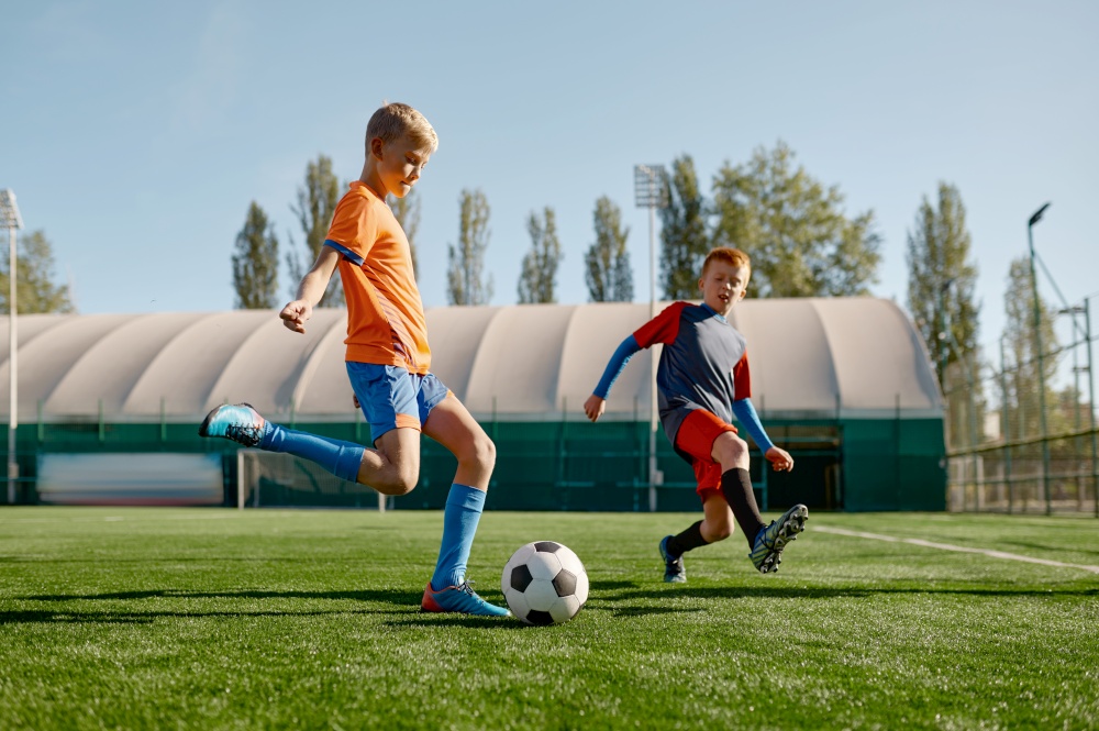 Portrait of school boys training soccer on football field. Two kids attacker and defender running with ball. Portrait of school boys training soccer on football field