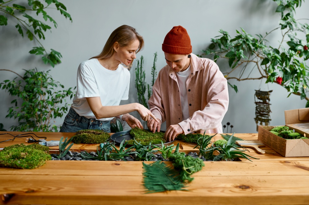 Professional florists working at creative art studio. Focus on young woman making composition from green fresh moss. Professional florists working at creative art studio
