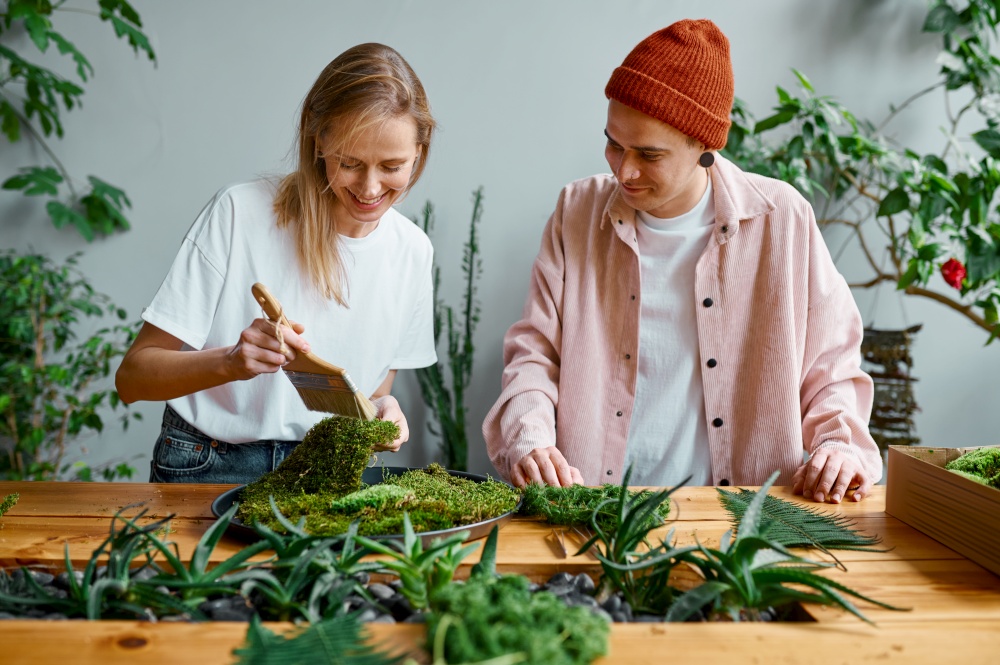 Young florists working at creative workshop. Millennial hipster man and woman making decoration from fresh herbs. Young man and woman florist working at creative workshop