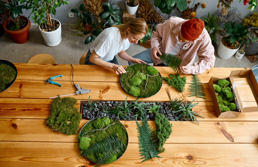 Professional floral decorator team working on fern and moss art piece. Top view. Professional floral decorator team working on fern and moss art piece