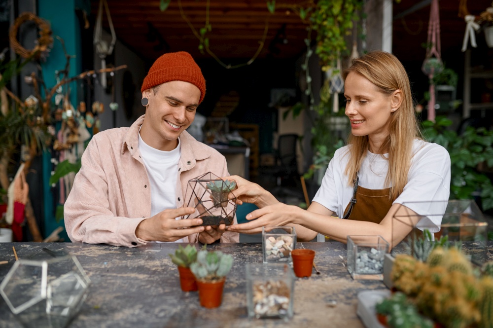 Young man and woman making composition in florarium vase. Happy florists family creating succulent plants composition. Happy man and woman making composition in florarium vase