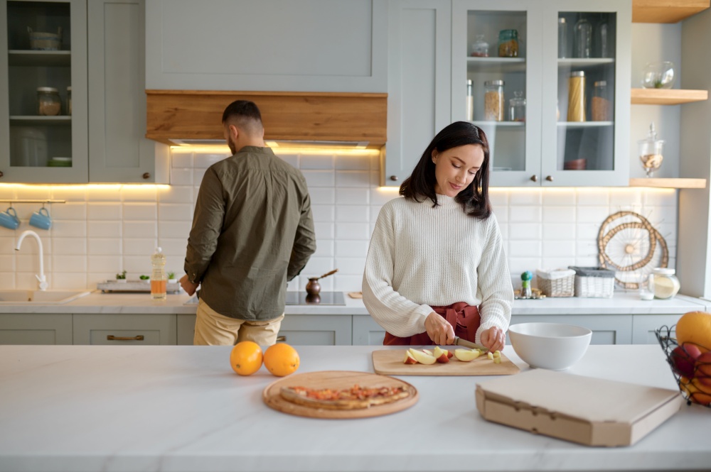 Young happy family preparing food on dinner or breakfast. Married couple cooking together on kitchen. Married couple cooking together on cozy home kitchen