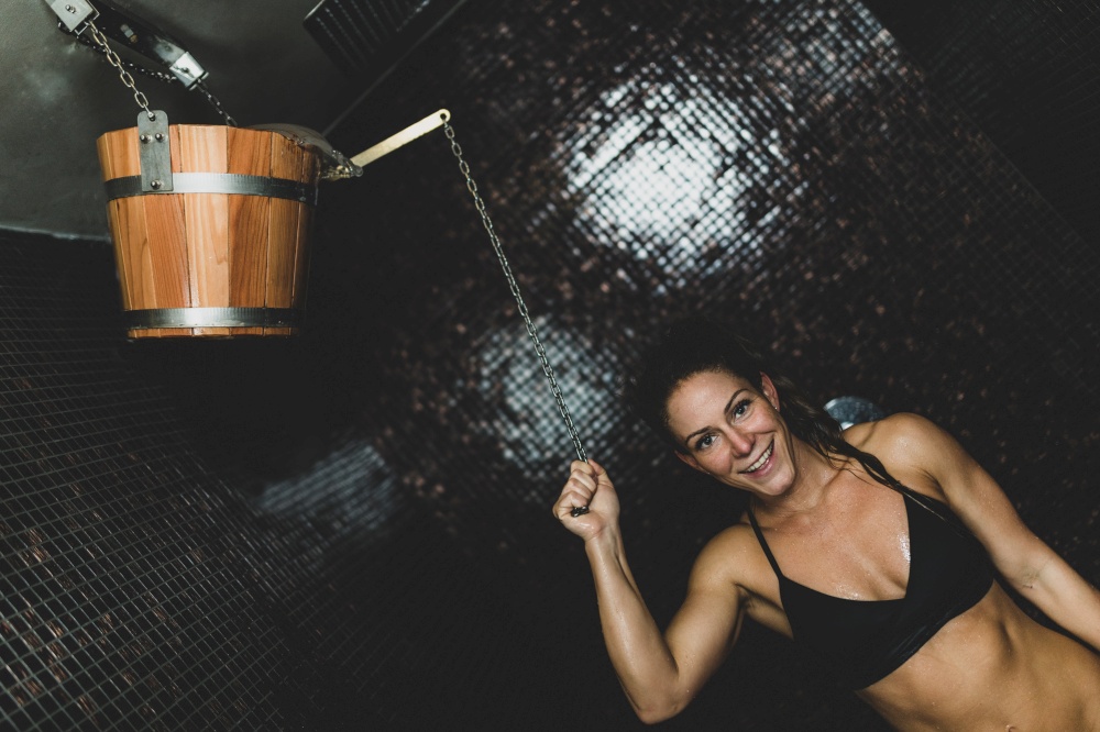 Wooden Bucket with Cold Water in Spa Center.. Woman Taking a Cold Shower from Ice Bucket.
