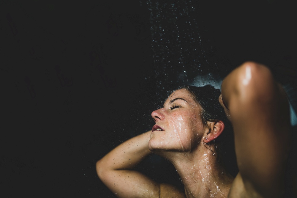 Woman under Water Drops. Showering, Black Background.. Attractive Woman Taking a Shower