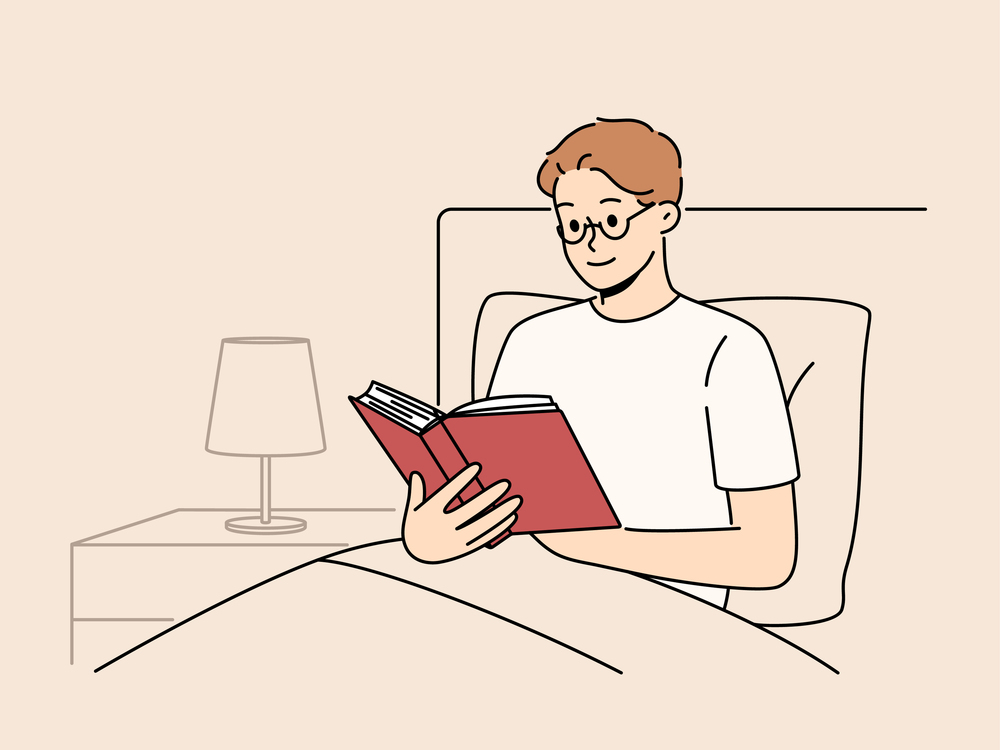 Man reads book before bedtime, sitting in bed at night and enjoying plot of fantasy novel. Smart young guy student preparing for exam in bed studying textbook with educational information. Man reads book before bedtime, sitting in bed at night and enjoying plot of fantasy novel