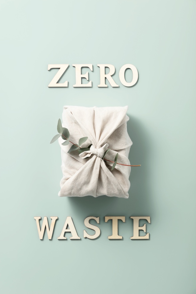 Eco-friendly reusable gift textile packaging with eucalyptus and wooden letters.  Sustainable gift wrapping. Zero waste