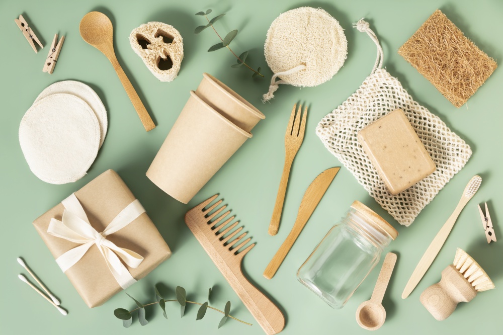 Set of reusable eco friendly products . Zero waste concept. Eco natural paper cups, bamboo cutlery, natural cleaning products on pastel green background, flat lay. Plastic free sustainable lifestyle concept. Set of eco-friendly tableware and cleaning products on pastel green background, flat lay stop plastic pollution