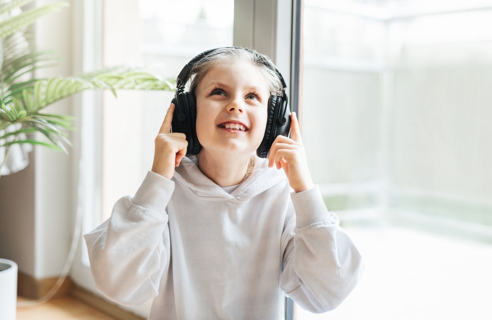 Cute little girl listening to music in headphones  at home.