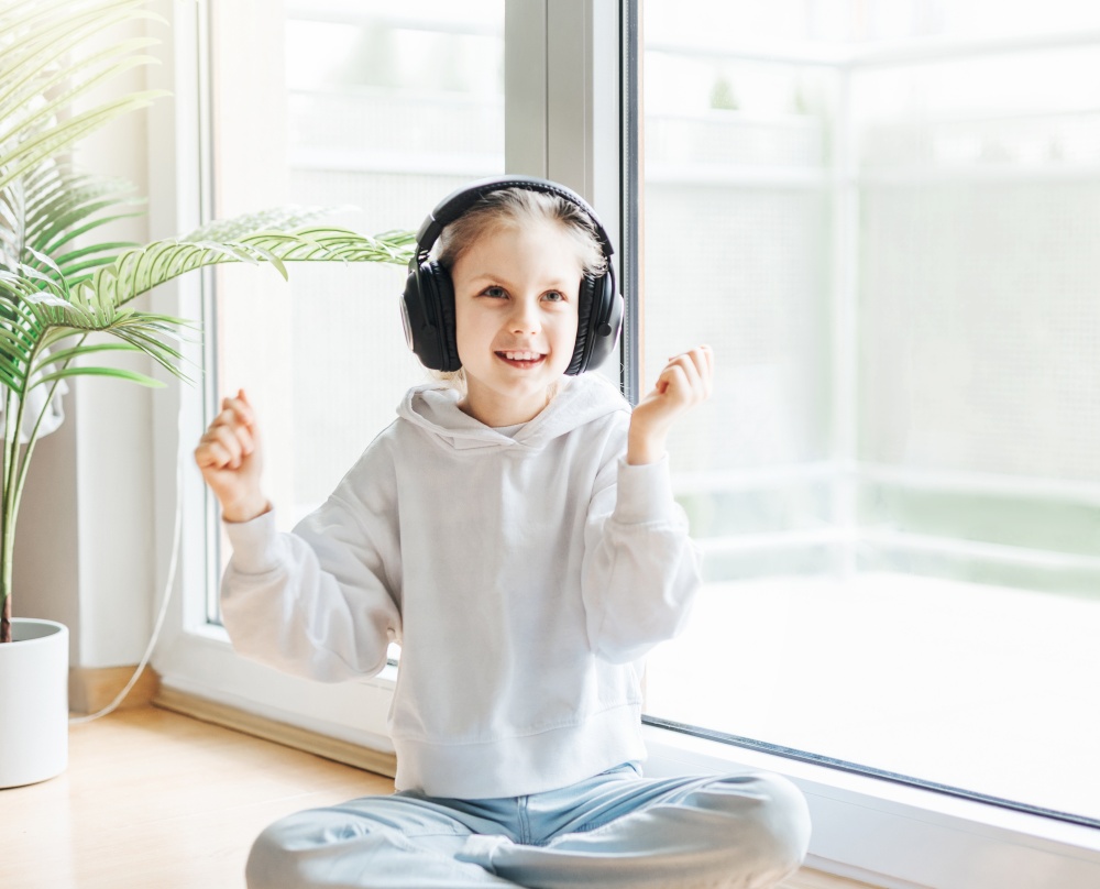 Cute little girl listening to music in headphones  at home.