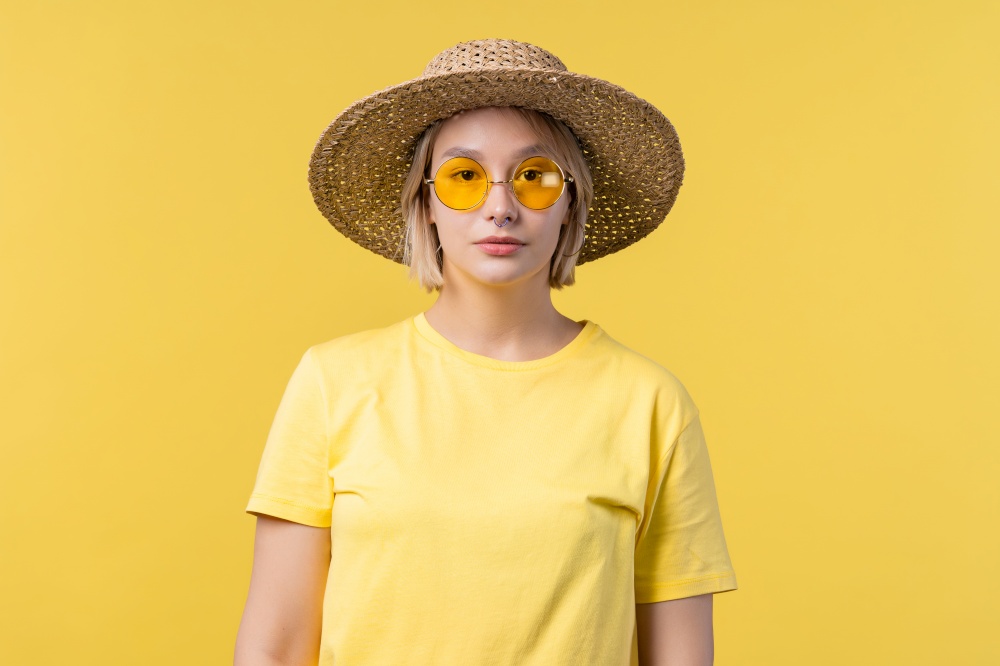 Portrait of young pretty blonde woman on summer yellow studio background. Confident sunny outfit with sunglasses and straw hat. High quality photo. Portrait of young pretty blonde woman on summer yellow studio background. Confident sunny outfit with sunglasses and straw hat.