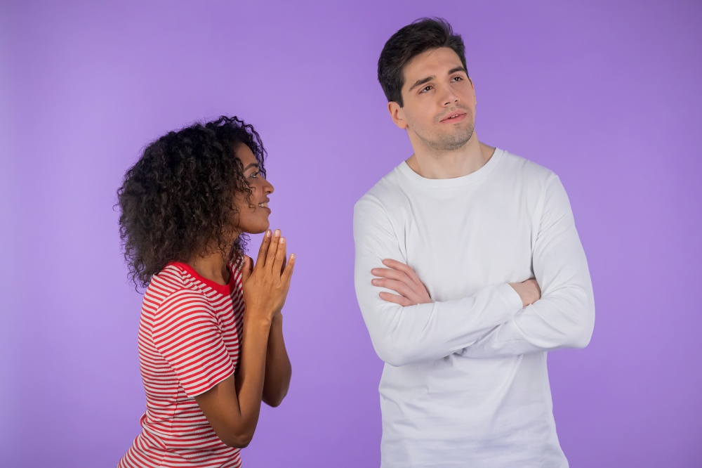 Cute african young woman begging her boyfriend or husband about something over violet background. Girl want her man to satisfy desires, help with. interracial couple. High quality photo. Cute african young woman begging her boyfriend or husband about something over violet background. Girl want her man to satisfy desires, help with. interracial couple