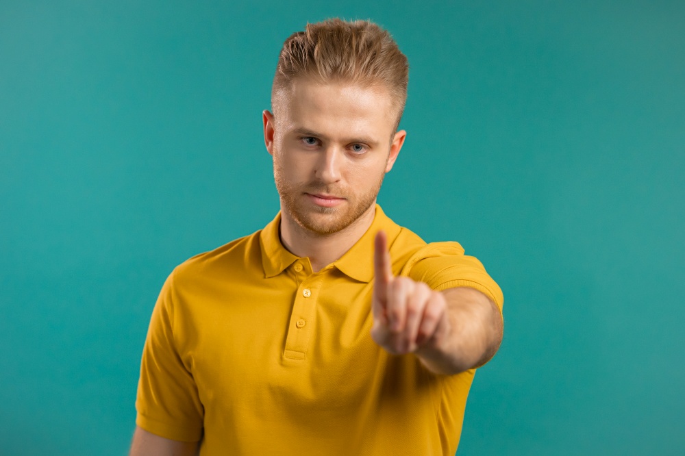Portrait of serious man showing rejecting gesture by stop finger sign. Guy isolated on blue background. High quality photo. Portrait of serious man showing rejecting gesture by stop finger sign. Guy isolated on blue background.