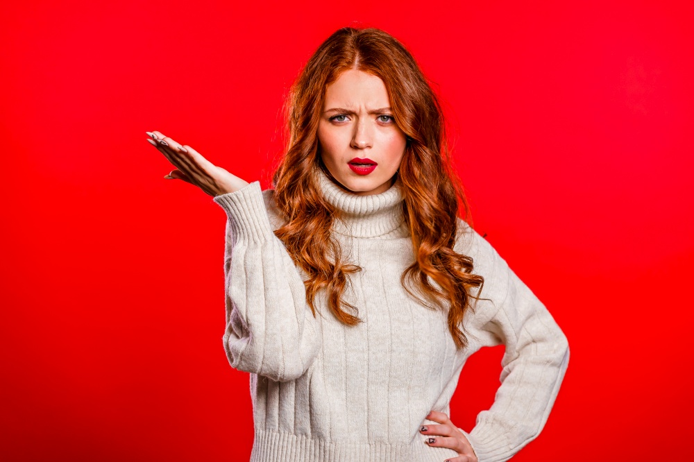Portrait of Irritated angry young woman isolated on red studio background. Girl spreading hand like question what. Portrait of Irritated angry young woman isolated on red studio background