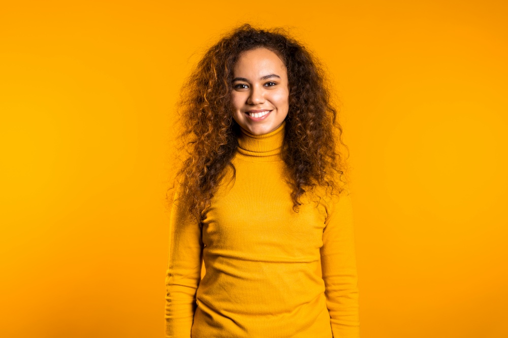 Young curly woman in total yellow look. Portrait of beautiful mixed race girl on studio background. Young curly woman in total yellow look. Portrait of beautiful mixed race girl on studio background.