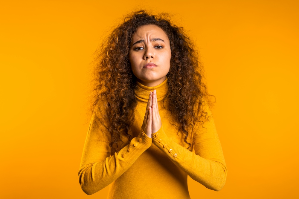Cute curly young girl praying over yellow background. Woman begging someone. 4k. Cute curly young girl praying over yellow background. Woman begging someone. 4k.